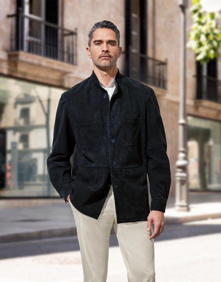 Veste en cuir de jeune renne Homme en veste en cuir de veau de renne noire, devant une architecture moderne en ville.