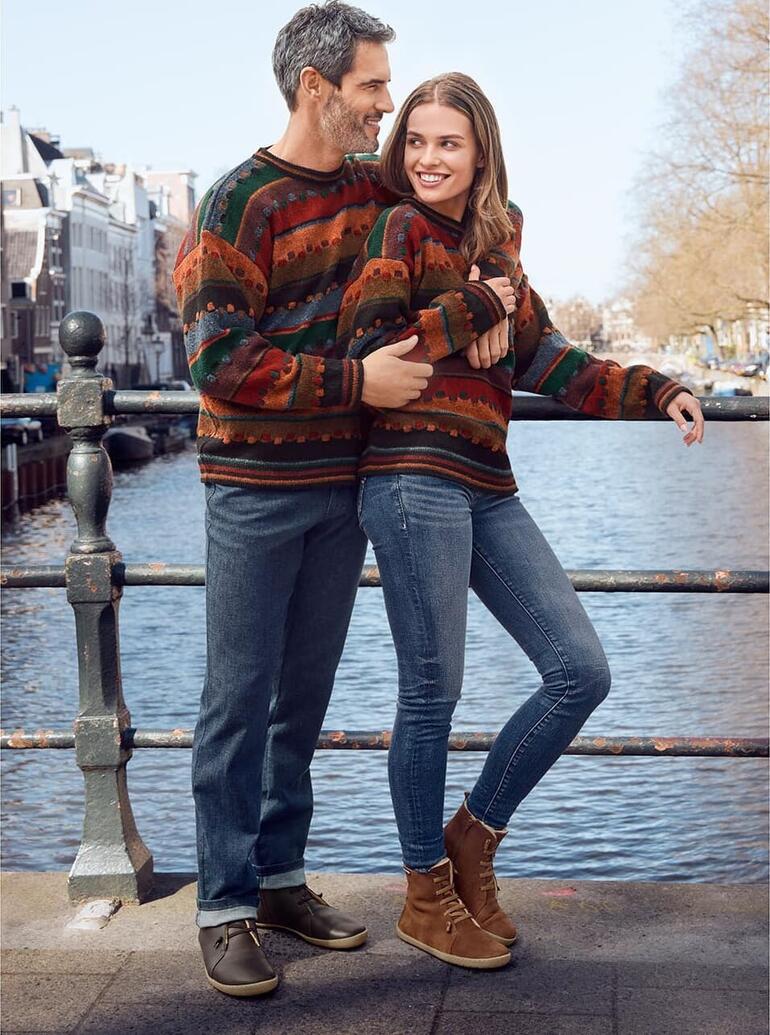 Couple en pulls colorés au bord d'un canal en ville.