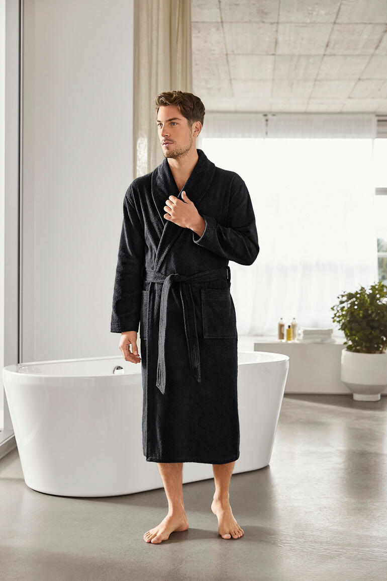 Homme en peignoir noir dans une salle de bains moderne