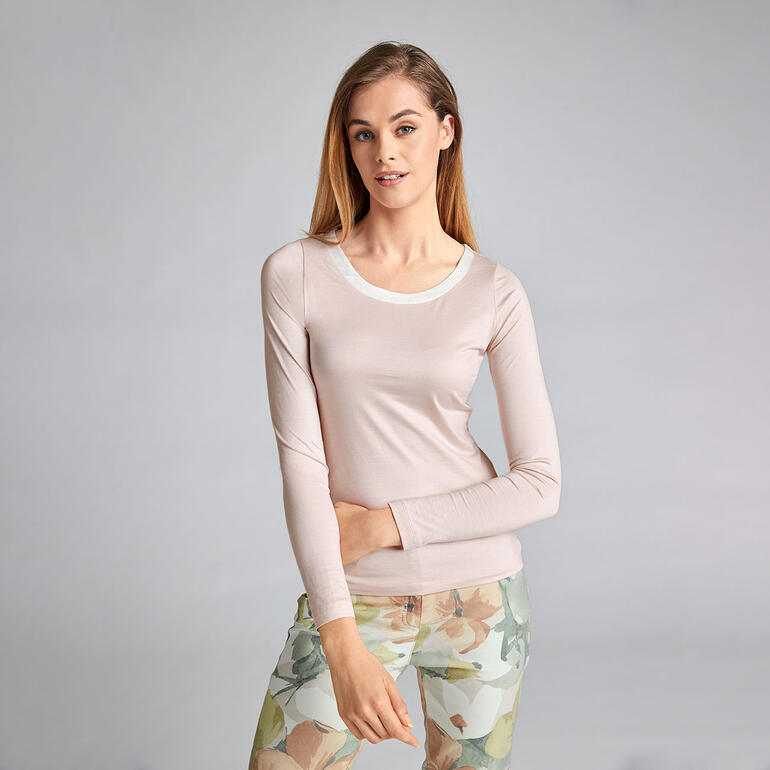 Femme en haut de soie rose pâle avec manches longues et encolure ronde.