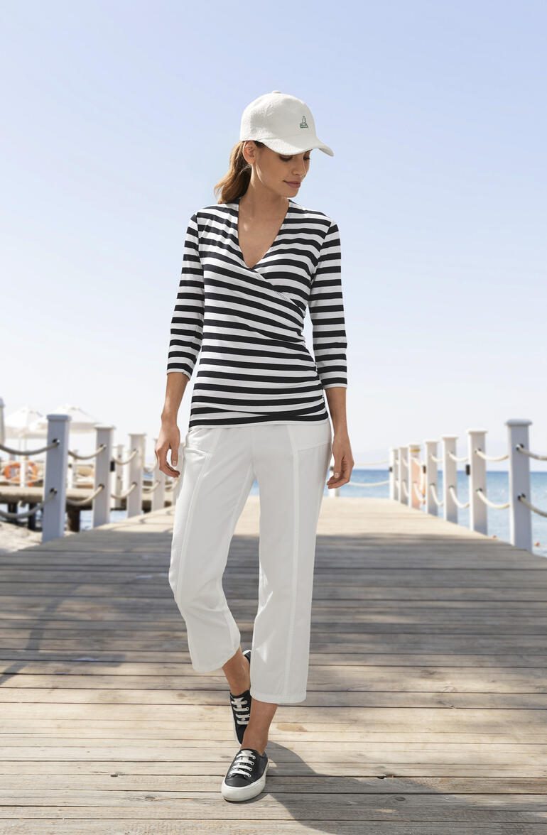 Noir Femme en blouse rayée et pantalon blanc, sur la plage.