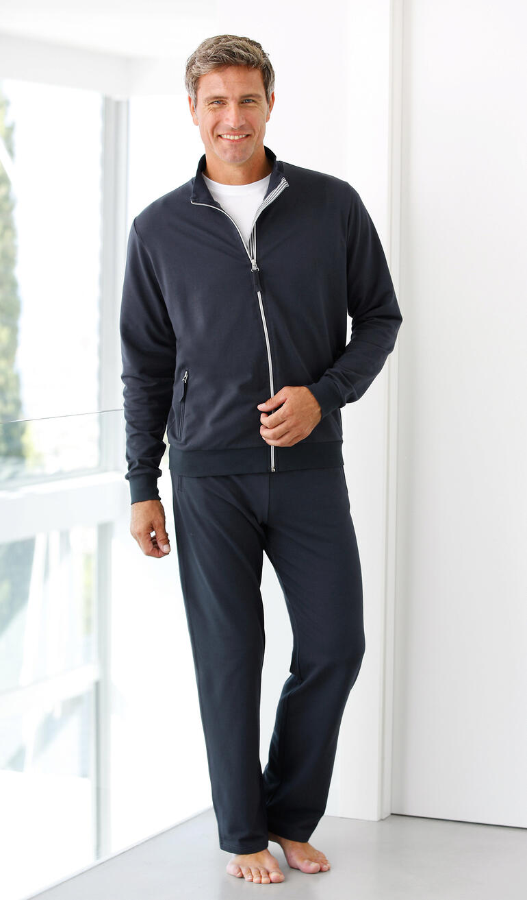 Homme en costume de fitness Coolmax bleu foncé, souriant et pieds nus.