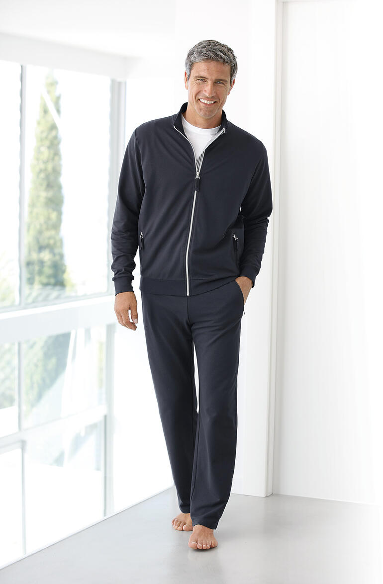 Homme en costume de fitness Coolmax bleu foncé, pieds nus debout dans un environnement lumineux.