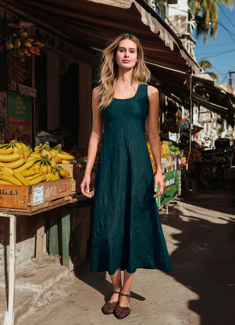 Robe soie crash brodée Femme portant une robe en soie crinkle verte brodée devant un marché.