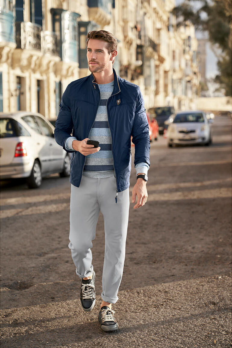 Pull blocs de rayure William Lockie Homme portant une veste bleue et un pantalon gris marchant vers une rue.