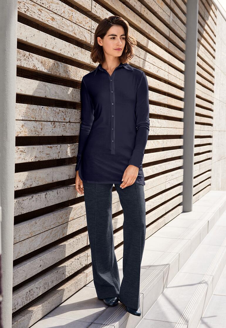 Chemise longue en Tencel bleu marine, appuyée contre un mur à l'extérieur.