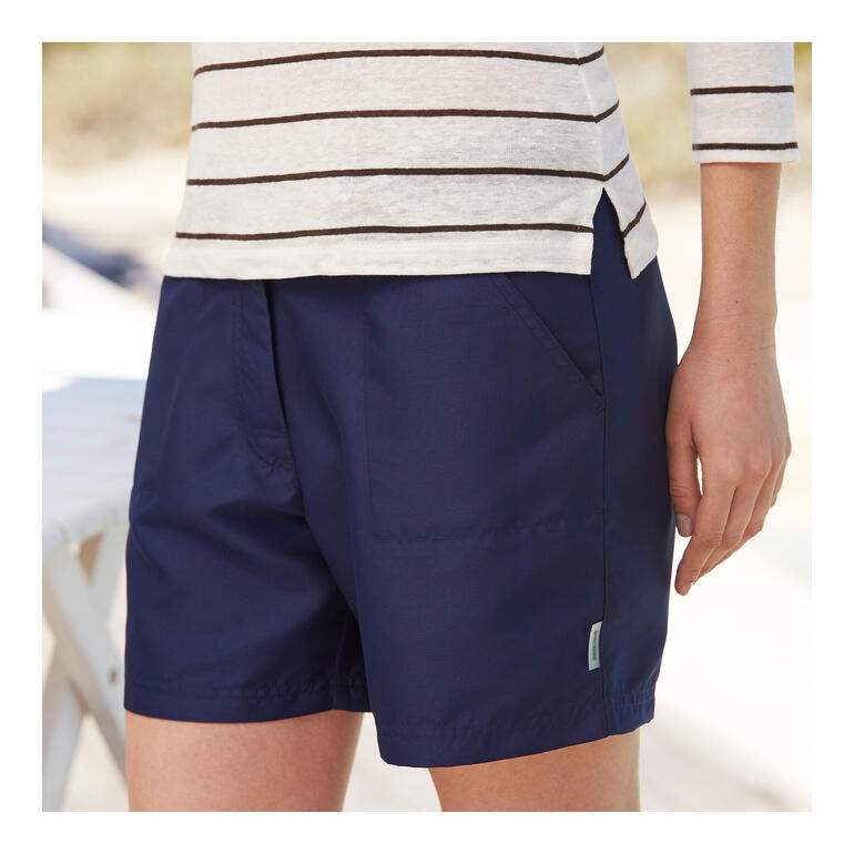 Gros plan sur des shorts en microfibre bleu marine portés par une femme à l'extérieur.