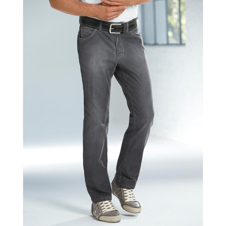 Homme en jean gris et T-shirt se tenant devant une fenêtre.