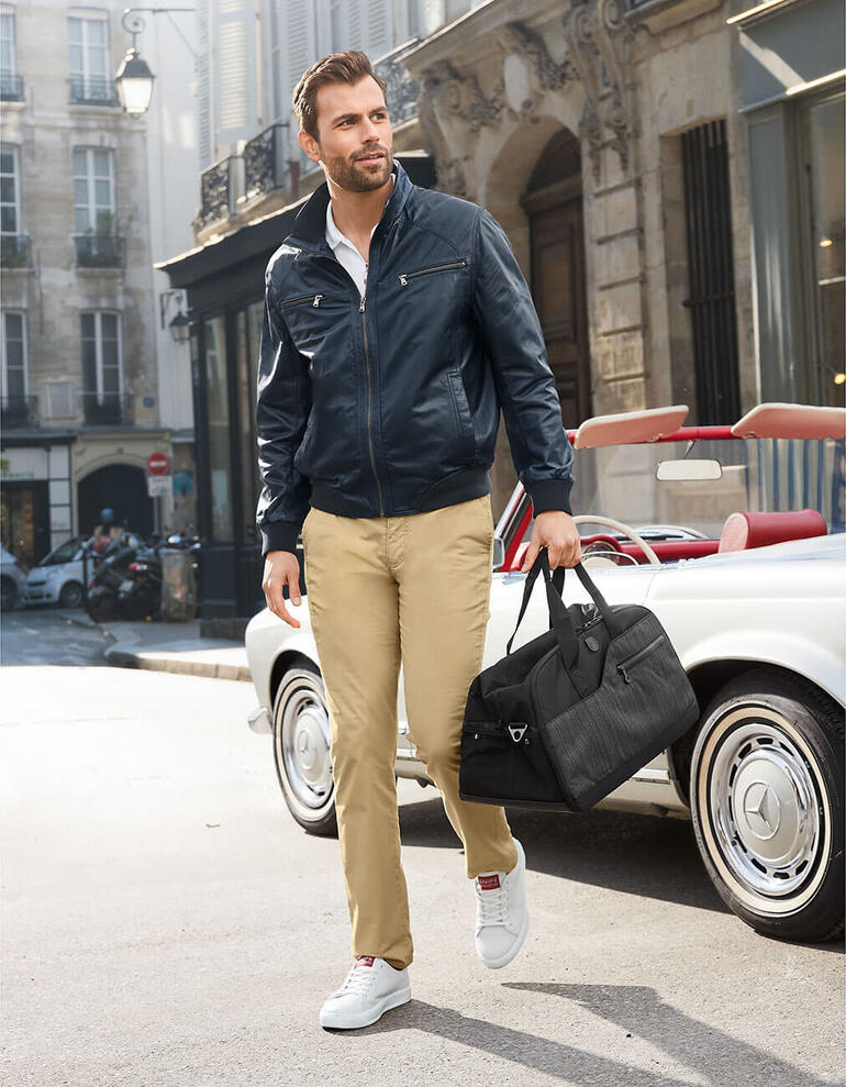 Blouson estival en cuir agneau nappa bleu Homme portant une blouson d'été en cuir bleu et un pantalon beige dans la rue.