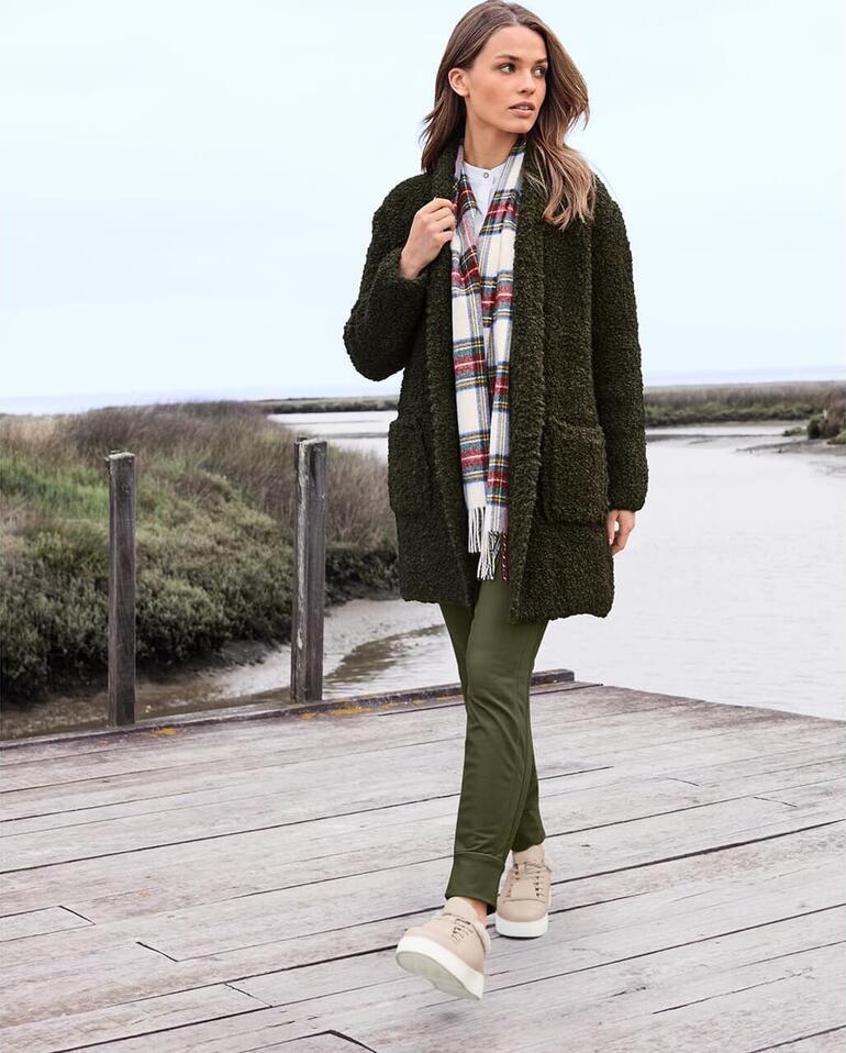 Femme marchant au bord de l'eau dans un pantalon de jogging thermo Stehmann et un cardigan.