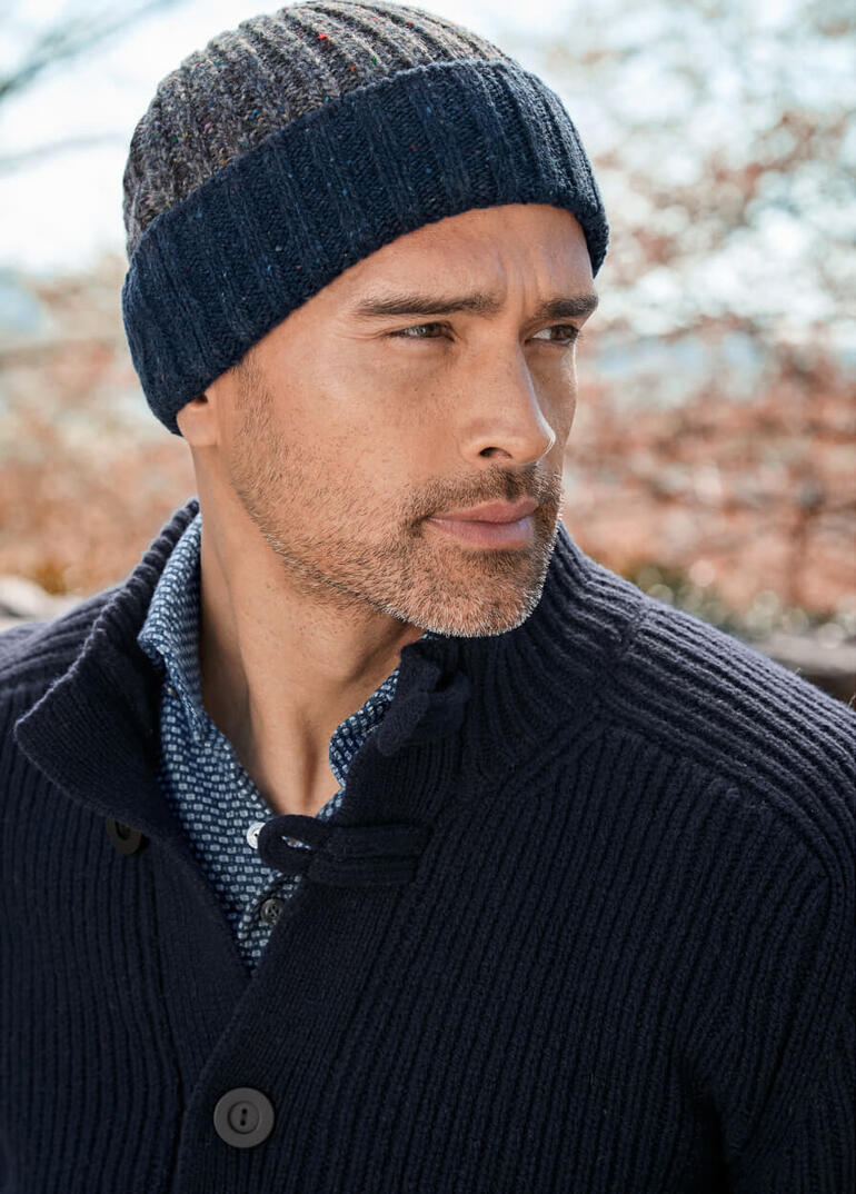 Homme portant un bonnet Donegal en laine à rayures, avec une expression neutre.
