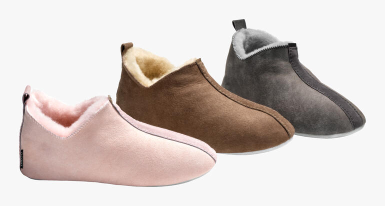 Trois paires de chaussons en peau de mouton dans différentes couleurs : rose, marron et gris.