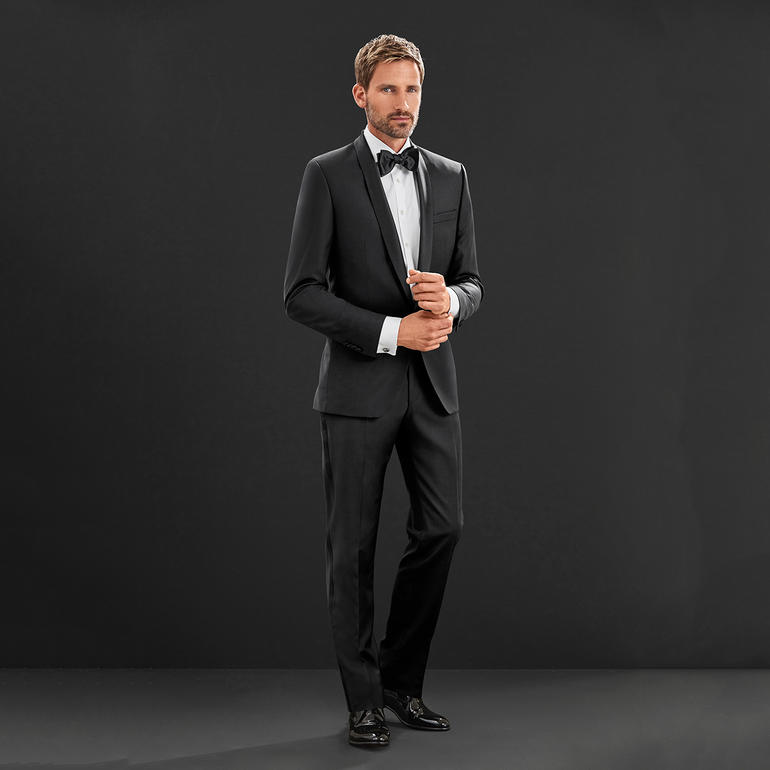 Homme en smoking avec nœud papillon sur fond noir