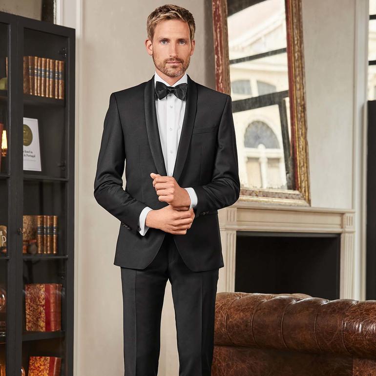 Homme en smoking avec nœud papillon dans une pièce élégante