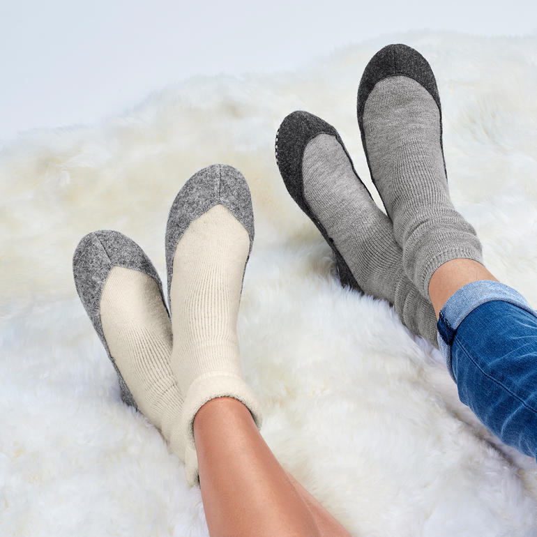 Pieds dans des chaussons grises et beiges.