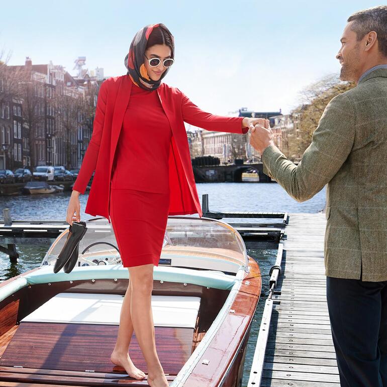 Femme en tenue rouge sortant d'un bateau au quai.