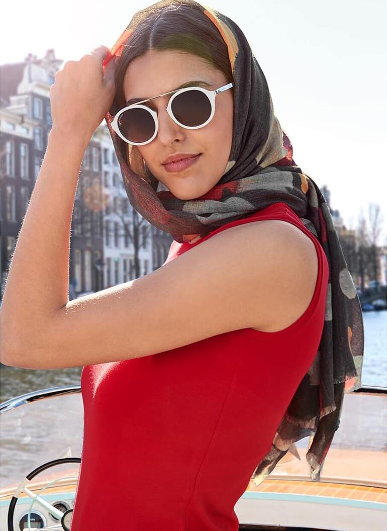 Gros plan d'une femme avec foulard sur la tête dans une robe rouge.