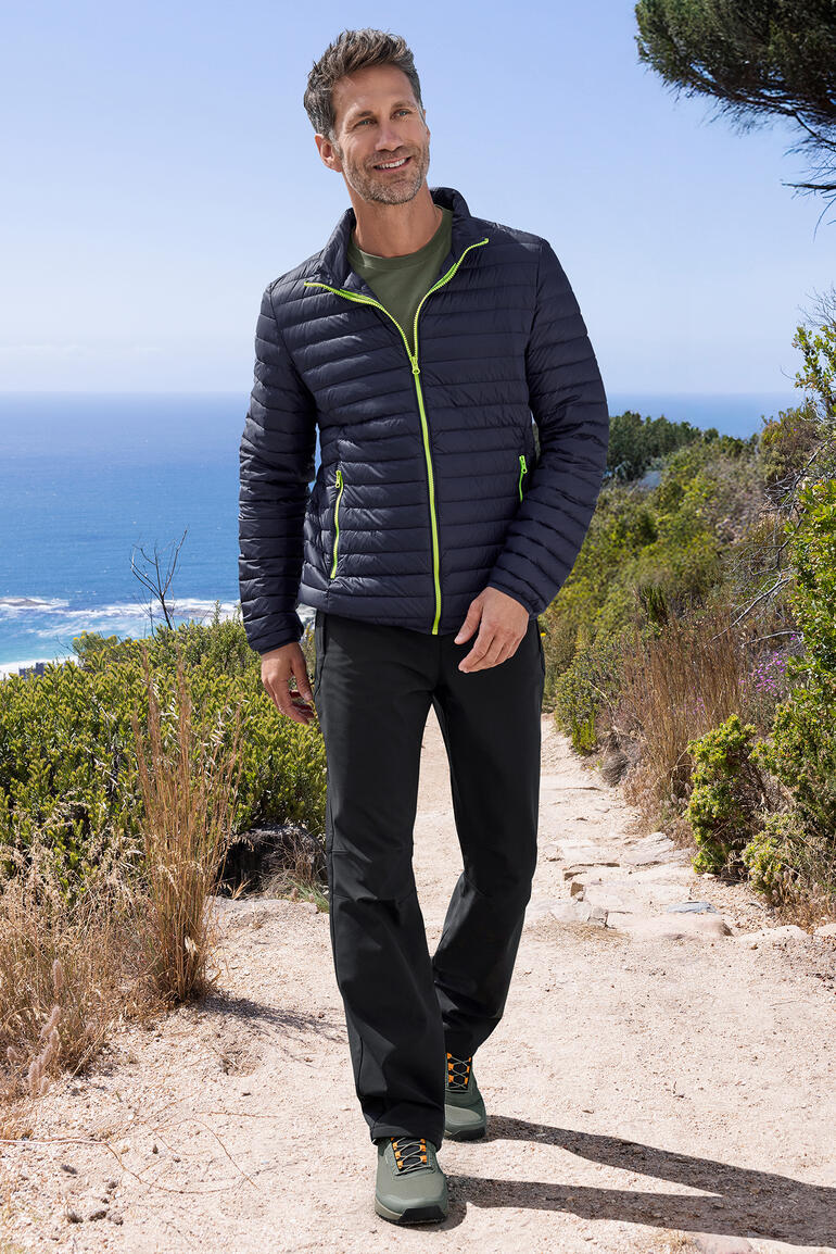 Veste d'été en duvet pour hommes en navy, portée par un homme en pleine nature avec vue sur la mer.
