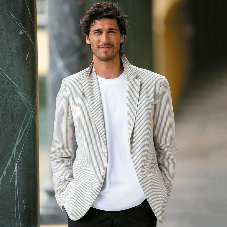 Homme portant un t-shirt blanc Ragman sous un blazer rayé.