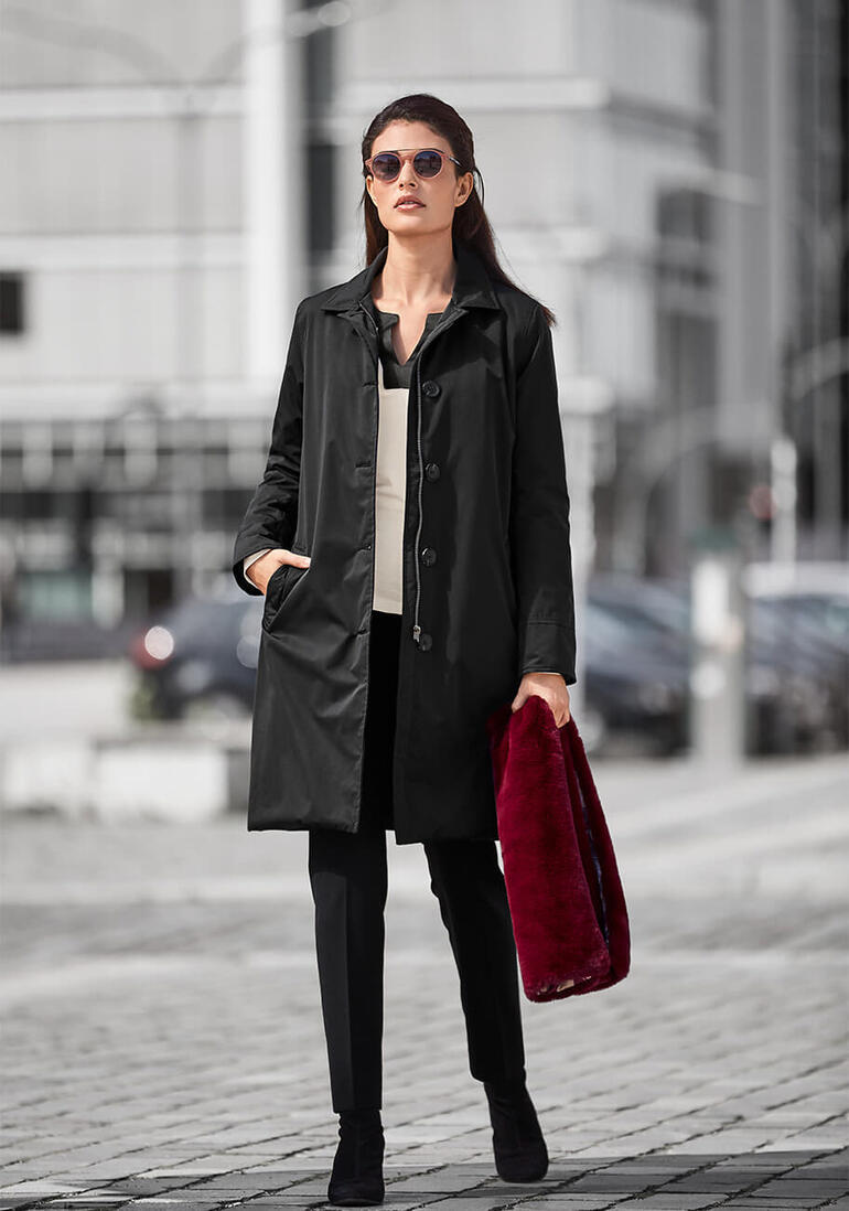 Travelcoat HappyRainyDays, Noir Femme en manteau de voyage noir avec des lunettes de soleil et un sac à la mode