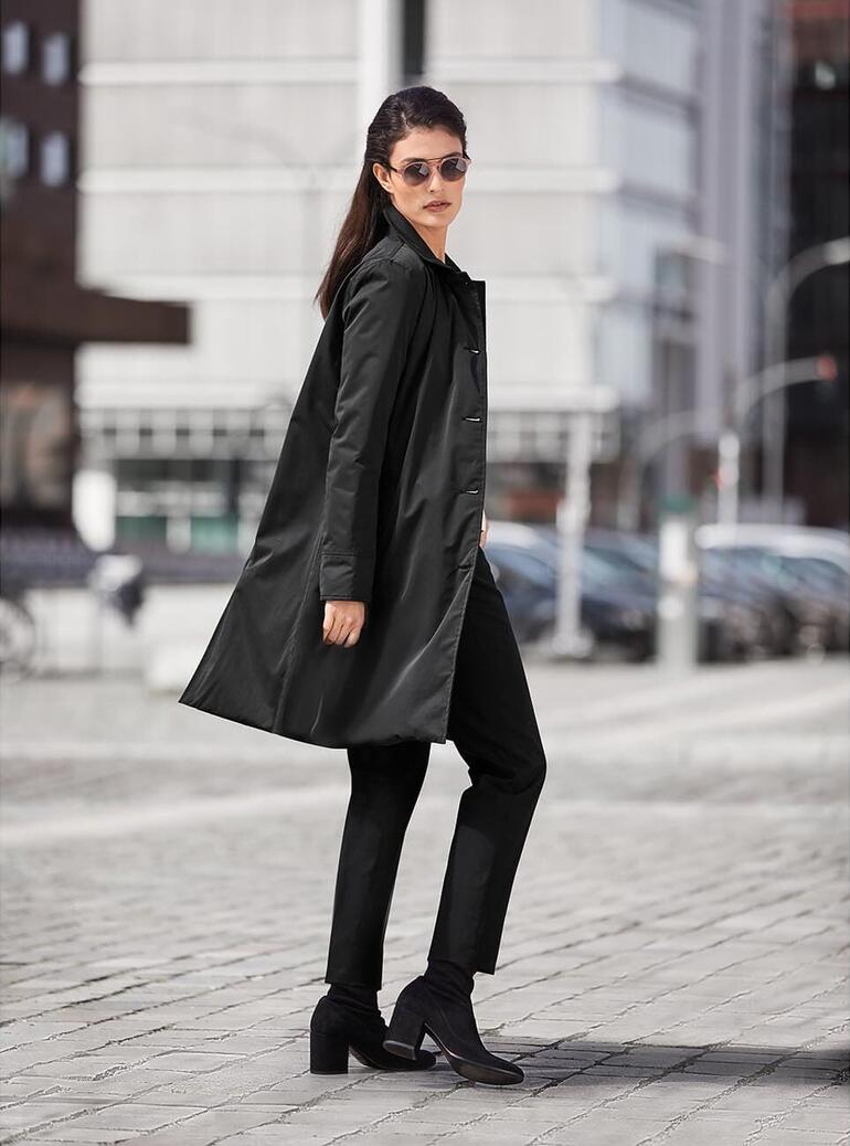 Femme en manteau de voyage noir dans un environnement urbain