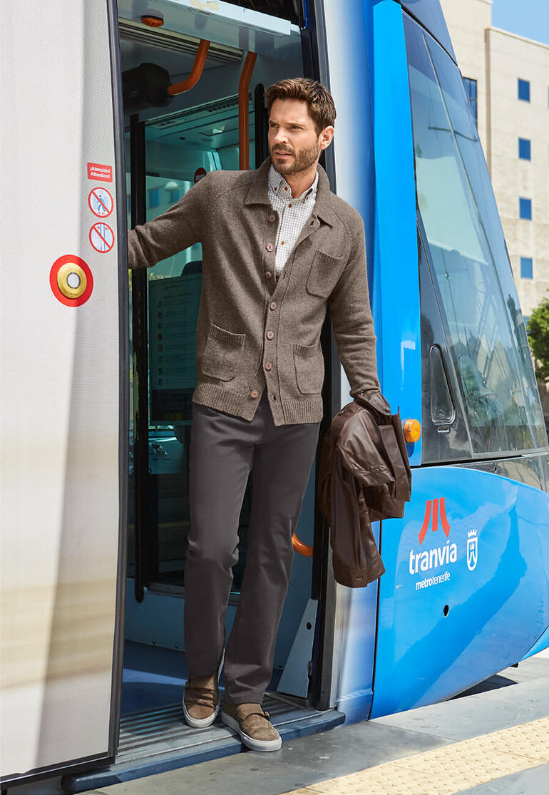 Cardigan noble Carbery Homme sort d'un tram en cardigan brun et pantalon clair