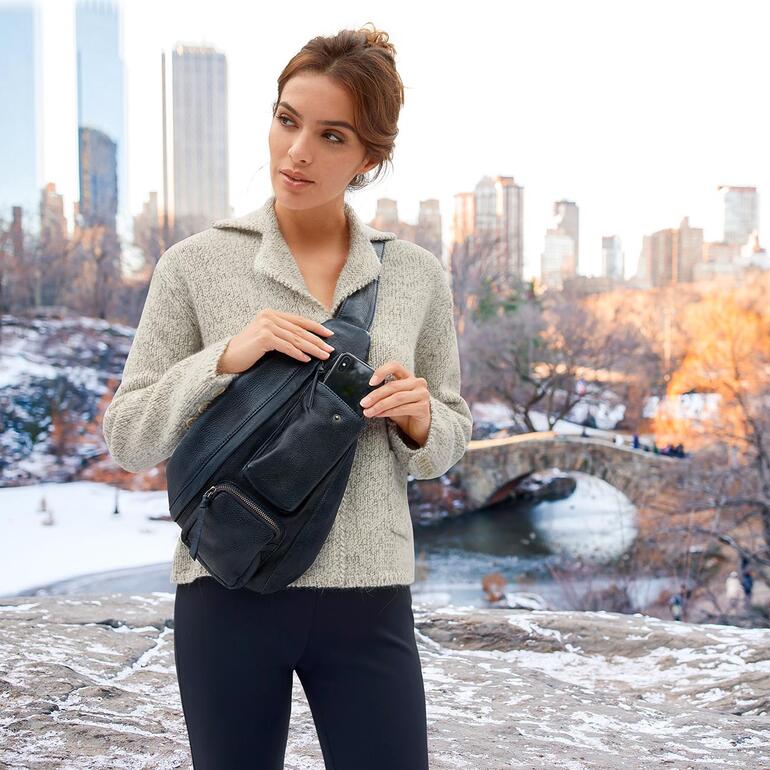 Femme avec un sac à bandoulière Anokhi dans un environnement hivernal avec un pont en arrière-plan.