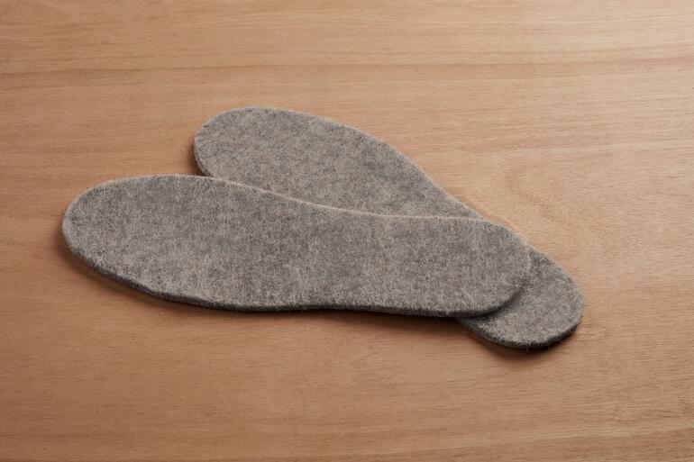 Deux semelles thermiques en alpaga grises sur un fond en bois.