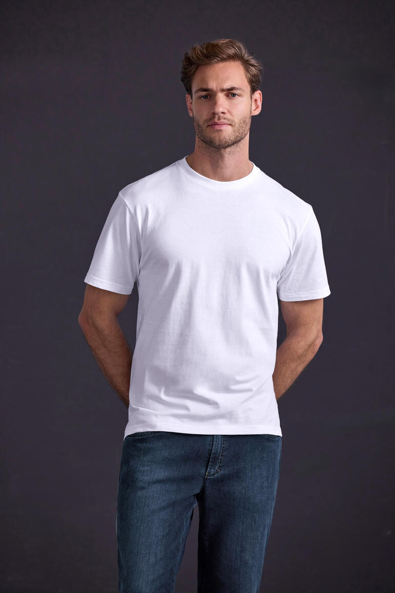 Homme en T-shirt blanc avec une posture décontractée devant un fond sombre.