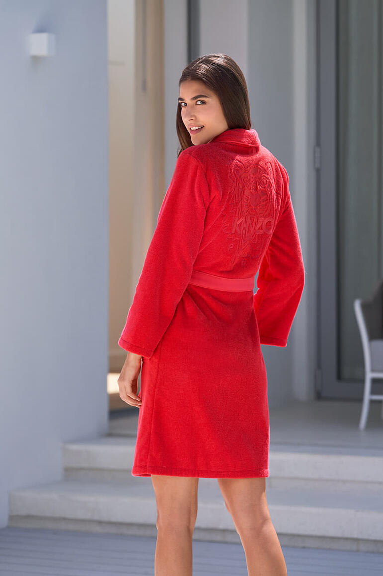 Vue arrière de la femme en robe de chambre rouge Kenzo sur une terrasse.