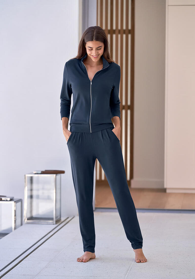 Bleu saphir Femme portant un ensemble maison modal bleu marine avec fermeture éclair se tenant dans une pièce moderne.