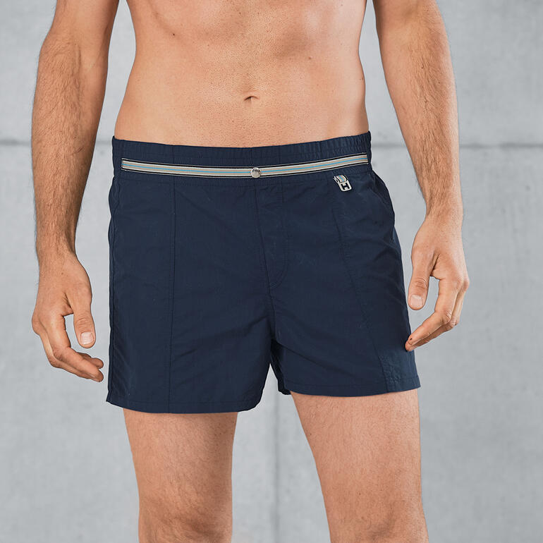 Short de bain HOM Homme portant un short de bain bleu marine avec taille élastique.