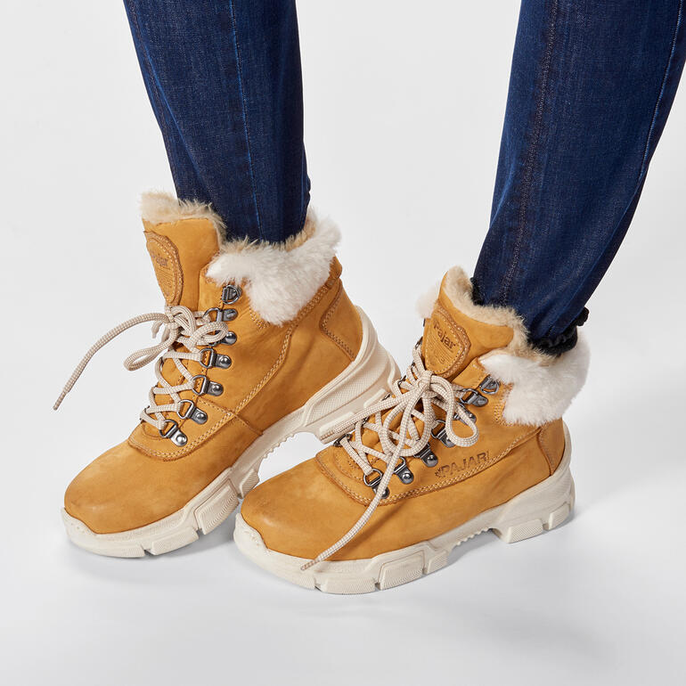 Bottes de randonnée brunes avec col en fourrure portées par une femme