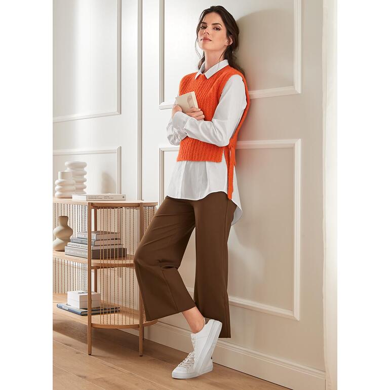 Pantalon à jambe large Punto Milano Pantalon large marron à la mode avec des baskets blanches, associé à un pull orange.