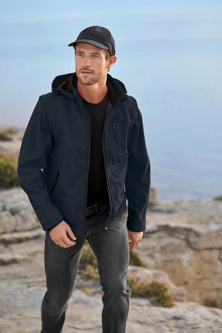 Homme en veste softshell noire au bord de la mer.