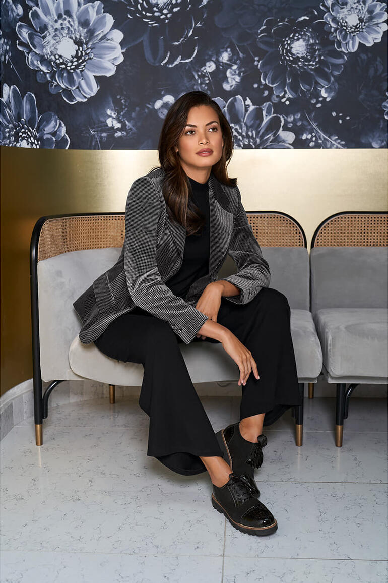 Noir/Gris Femme en blazer en velours lavable avec motif pied-de-poule sur un canapé.
