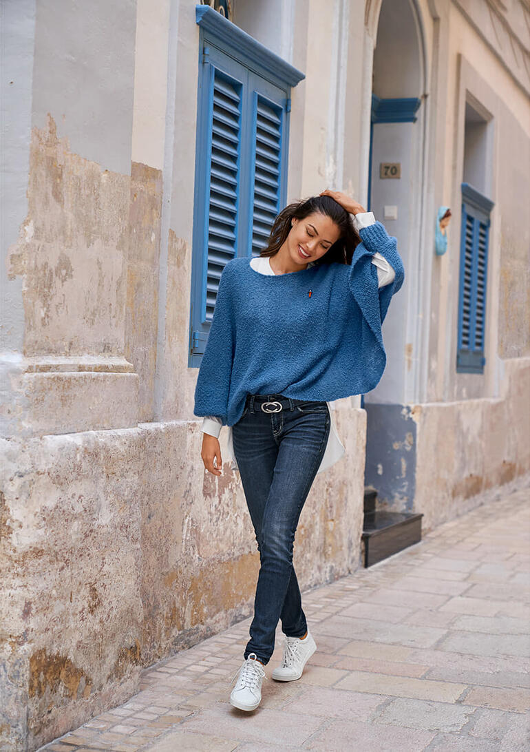Bleu Femme portant un pull poncho en bouclé bleu dans une rue de vieille ville