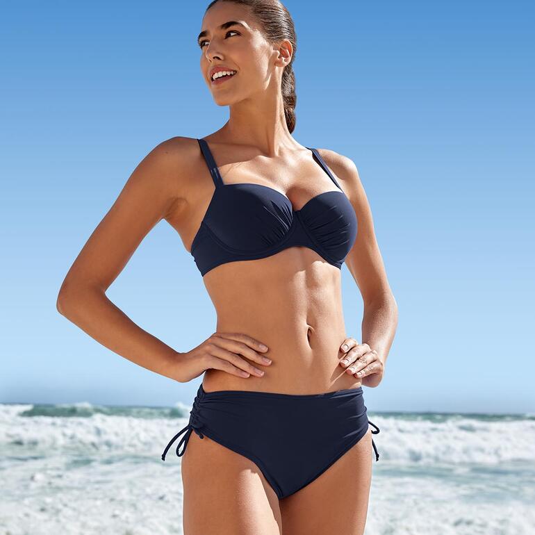 Bikini Sunflair® ReNew bleu foncé porté par une femme sur la plage.