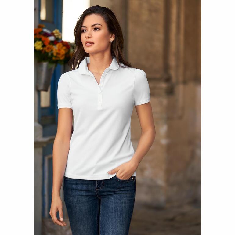Femme portant un polo blanc, associé à un jean foncé, devant un décor historique.