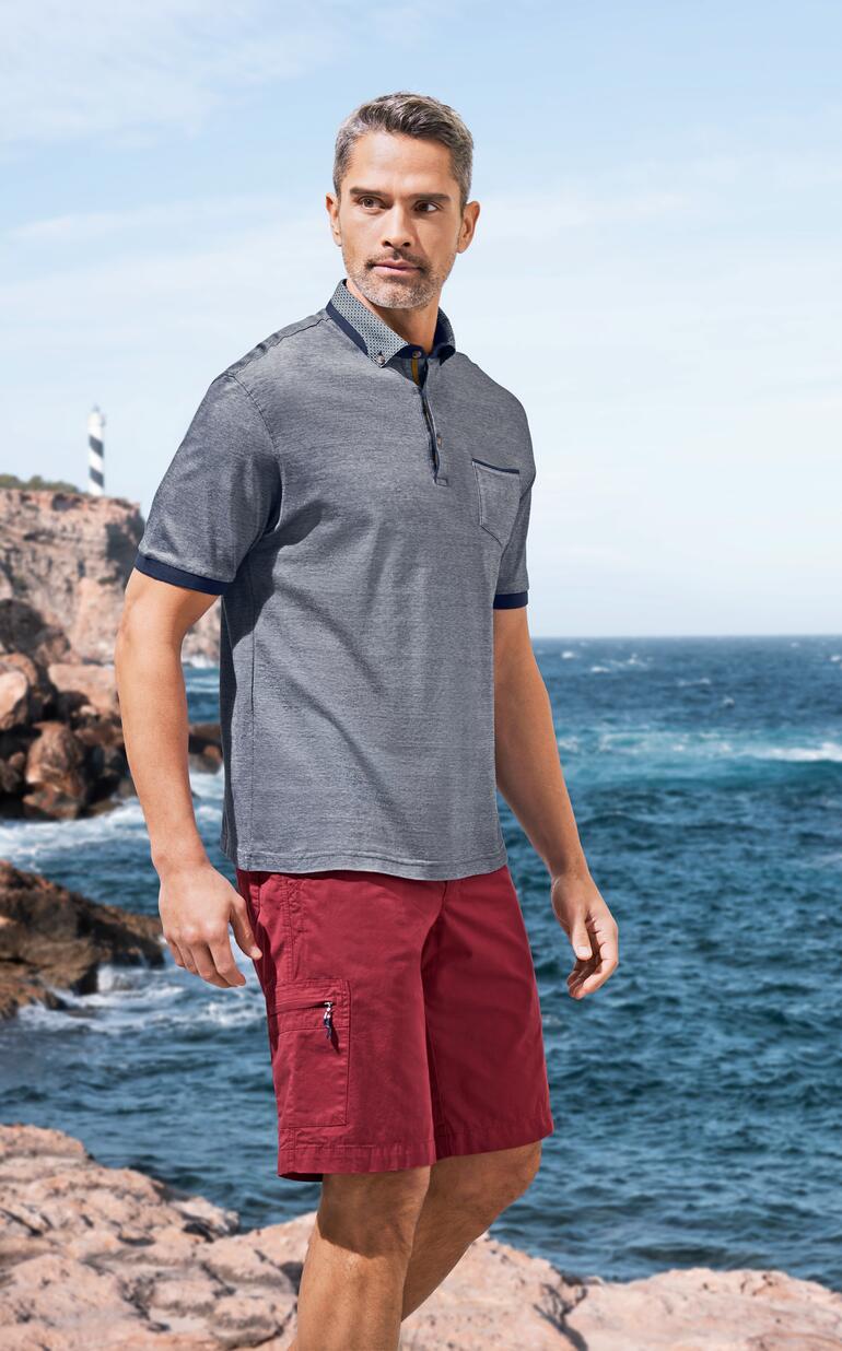 Homme portant un polo et bermudas rouges sur la plage.