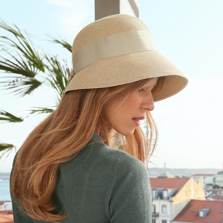 Femme portant un chapeau d'été beige à bord dans un environnement urbain