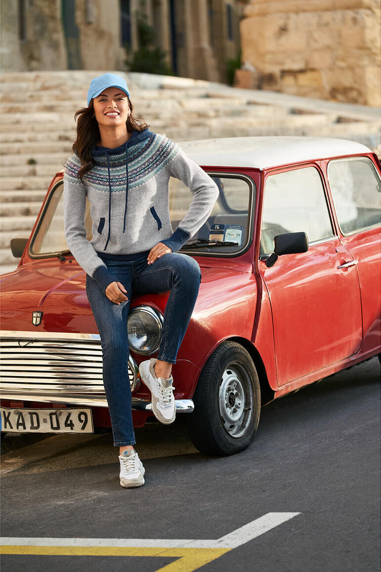 Femme assise sur une voiture rouge avec des sneakers vintage Satorisan.