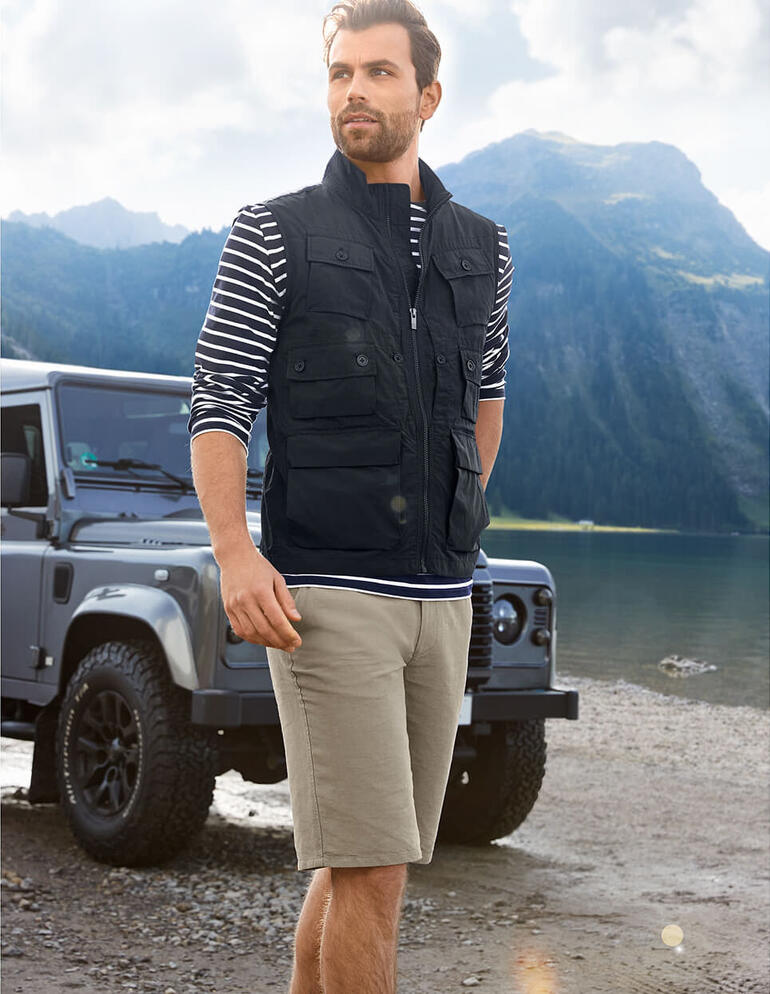 Gilet 10 poches Homme en gilet à 10 poches noir et chemise rayée au bord d'un lac de montagne.