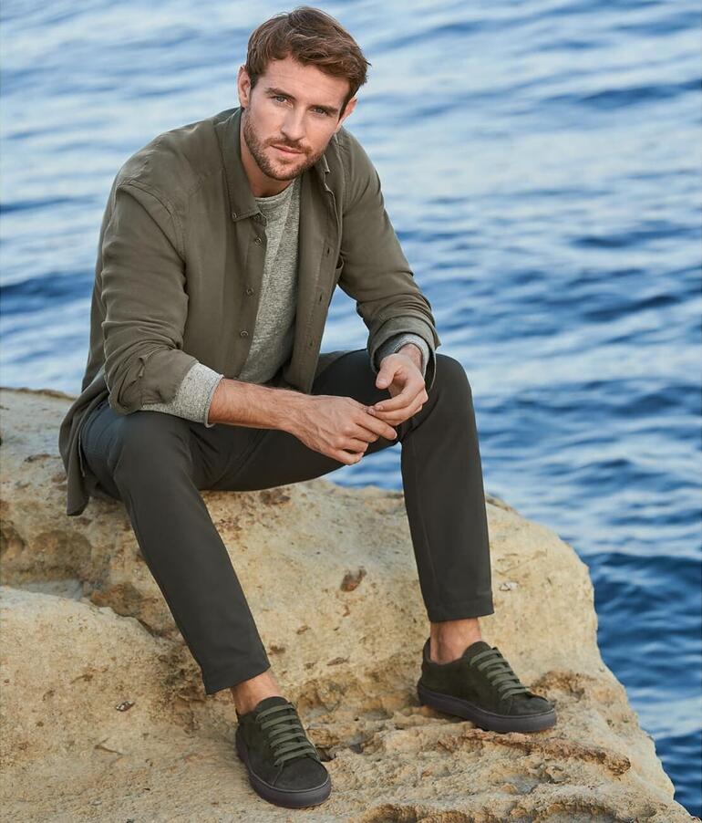 Homme en chemise en denim Tencel™ assis au bord de l'eau.