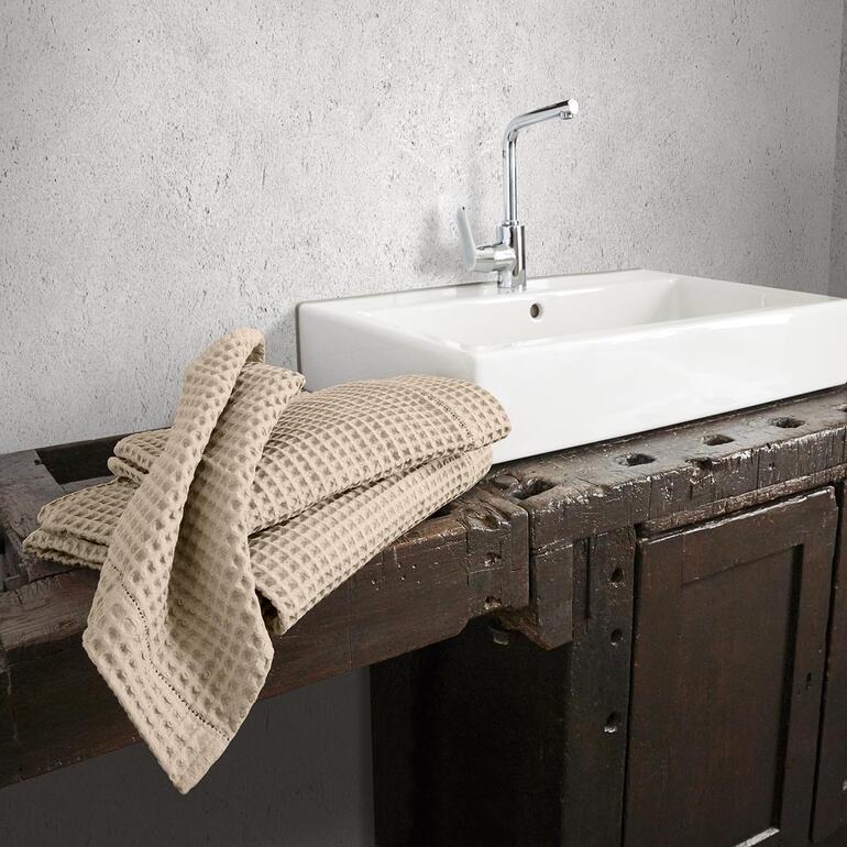 Serviettes en piqué gaufré beige posées sur une surface en bois.