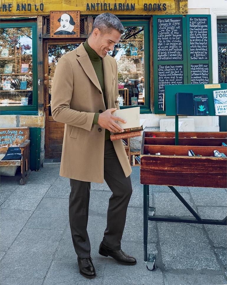 Camel Homme en manteau en cachemire beige, debout devant une librairie