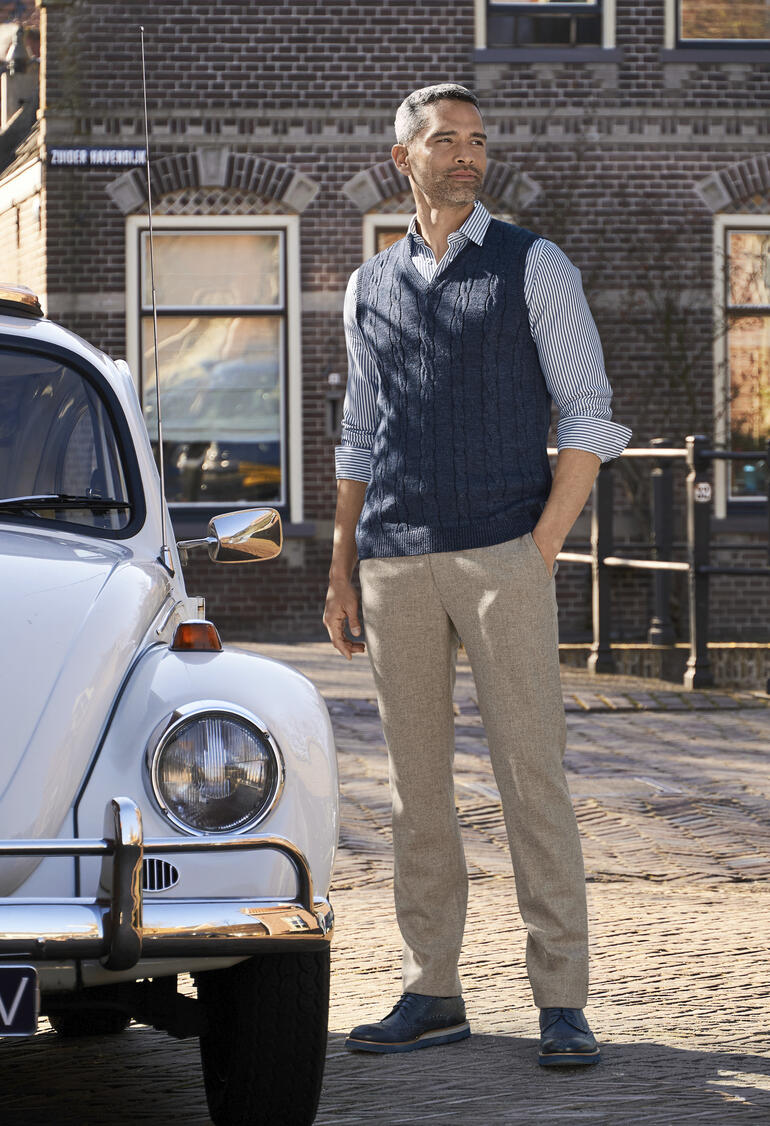 Bleu Homme en pantalon en feutre fin gris clair devant une voiture historique.