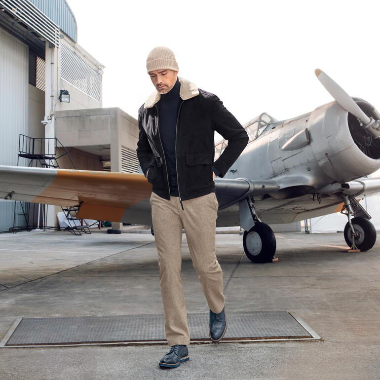 Beige Homme en pantalon en feutre fin devant un avion