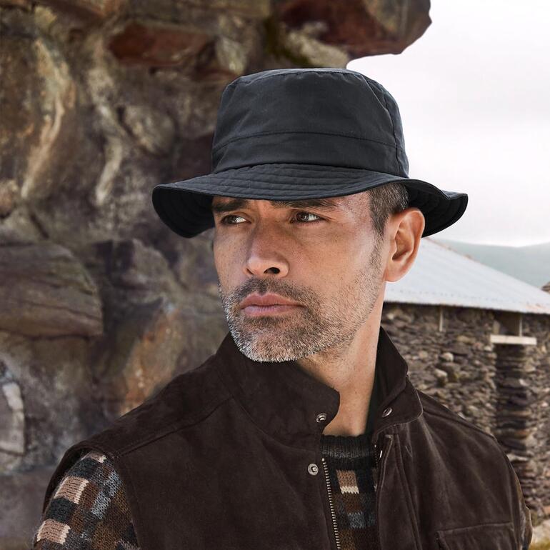 Chapeau intempérie en coton Mayser Homme portant un chapeau imperméable noir à l'extérieur.