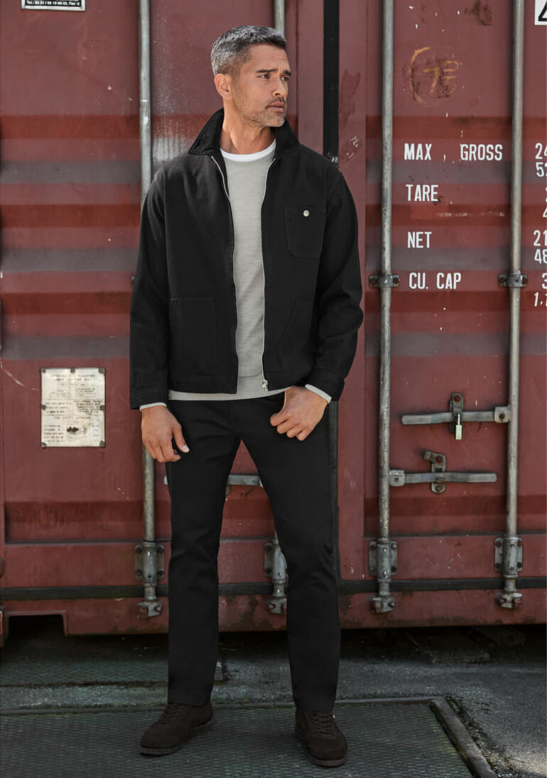 Veste en jean selvedge Edwin Homme en veste en jean Edwin Selvage noire devant un conteneur.